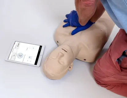 Student performing chest compressions on a Brayden Pro manikin with the feedback app running on a tablet